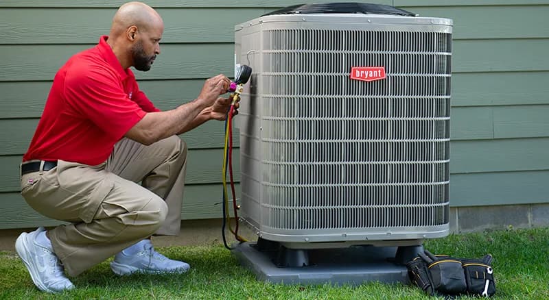 Bryant dealer inspecting a heat pump system outside a home
