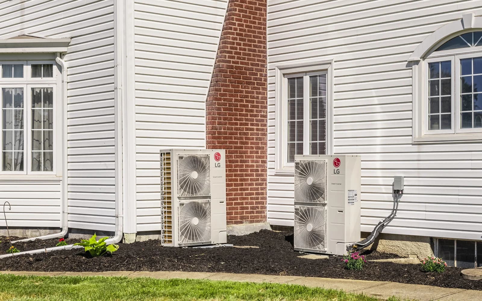 LG heat pump outdoor units installed beside a white home