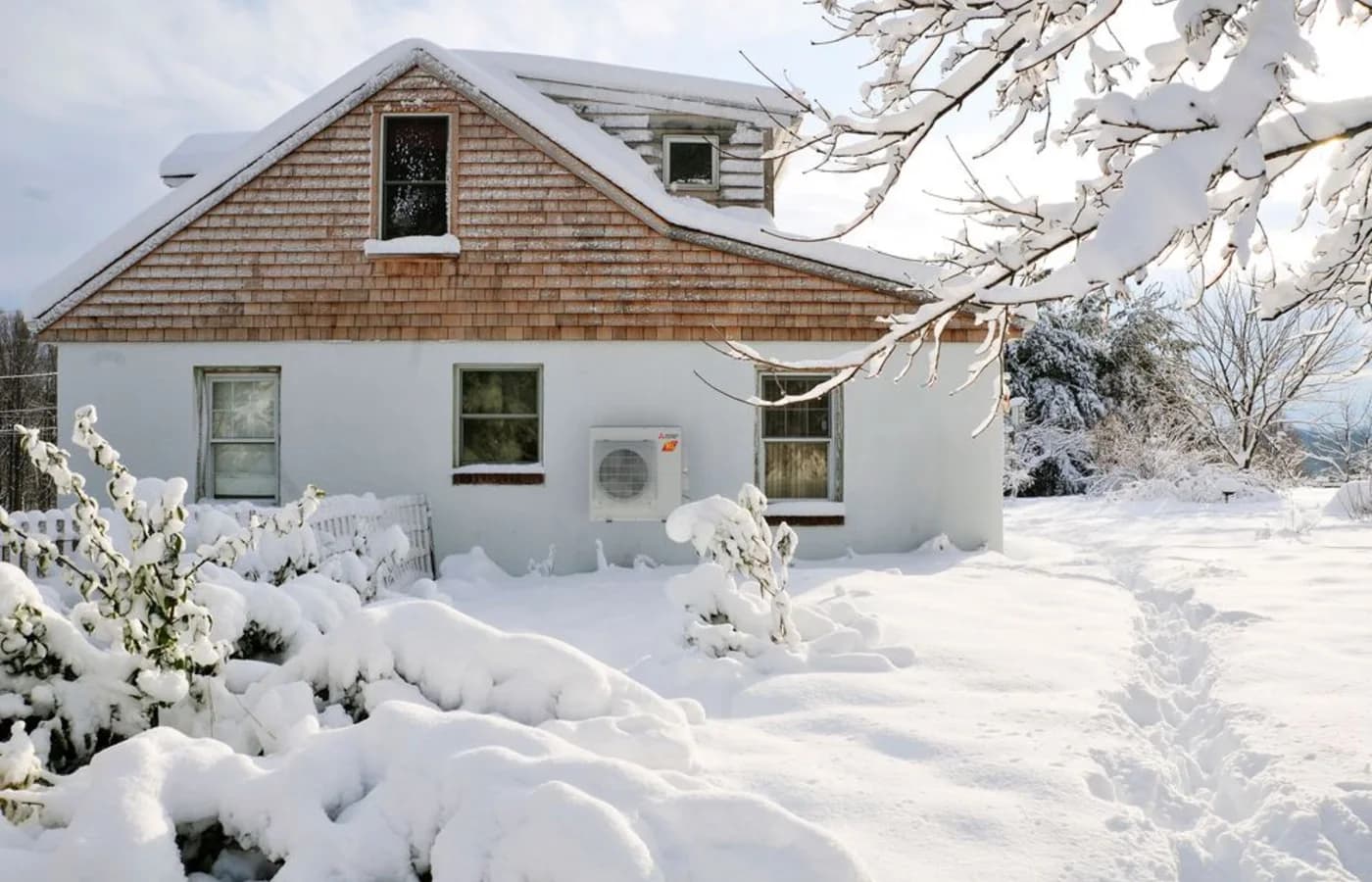 Mitsubishi Hyper-Heating outdoor unit operating beside a snowy home